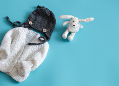 Knitted baby clothes and accessories on a blue background .